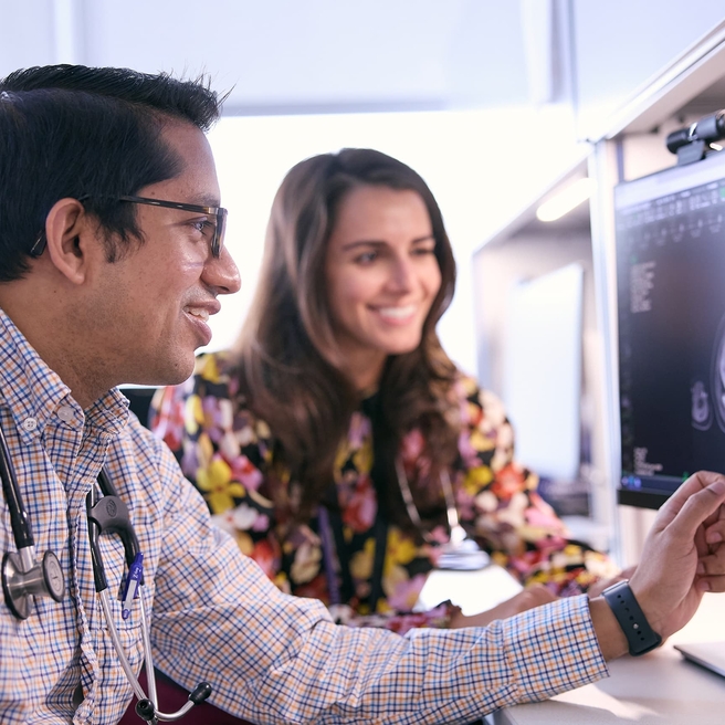 Two doctors analyzing a patient's scan on a hospital computer screen.