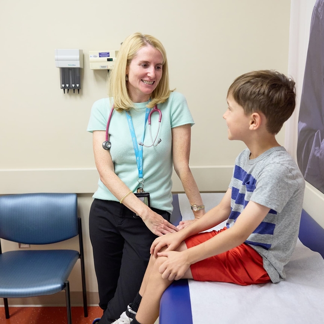 Doctor and patient talking and smiling at each other in an exam room.
