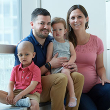 Young boy cancer patient in hospital window with his family