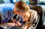 Father placing baby in car seat