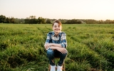 Carter, an 8th grader who had CDH surgery as a baby, sits in a field at home in Missouri