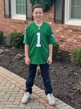 Hugh stands outside in his green Eagles jersey