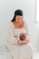 The baby is in her mother's arms.