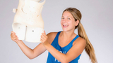Lindsay holding up her back brace