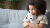 Scared young girl holding a stuffed animal Scared young girl holding teddy bear