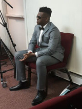 boy wearing suit sitting in chair at ceremony