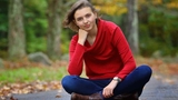 Ellie in a red sweater sitting on the gound