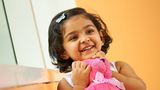 Young girl holding a pink stuffed bear
