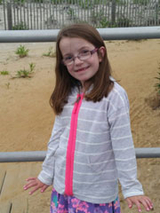 Emma at the beach wearing a sweatshirt smiling