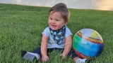 Alex smiling and sitting in the grass