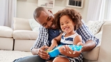 Father helping young daughter play ukulele Father helping young daughter play ukulele