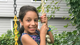 Isabella smiling and holding on to a rope swing