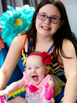Milana sitting and smiling with her older sister