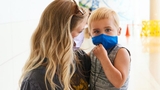 Mom holding son, both in masks Mom holding son, both in masks