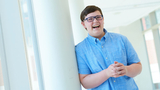 Young boy cancer patient sitting by window smiling