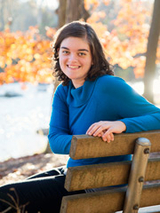 Sara sitting on a bench smiling outside