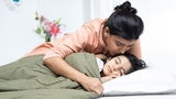 Mother kissing sleeping child on cheek
