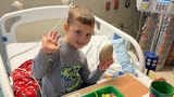 Rafi in the hospital bed smiling