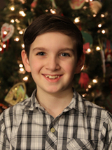 Zac smiling standing in front of a christmas tree