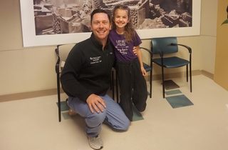 The kid and her doctor are taking a photo together.