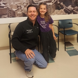 The kid and her doctor are taking a photo together.