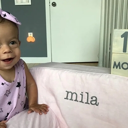 Smiling toddler in pink leaning on pink chair