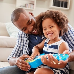 Father helping young daughter play ukulele Father helping young daughter play ukulele