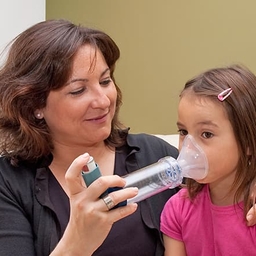 Mother helping daughter with inhaler Mother helping daughter with inhaler