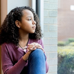 Adolescent girl sadly looking out window Adolescent girl sadly looking out window