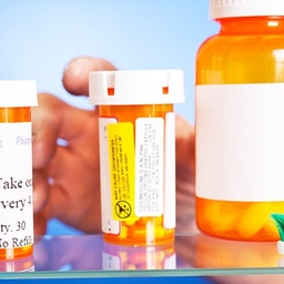 Hand reaching into medicine cabinet with pill bottles Hand reaching into medicine cabinet with pill bottles