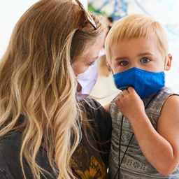 Mom holding son, both in masks Mom holding son, both in masks