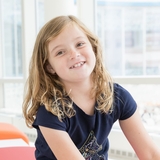 Smiling blonde girl with freckles wearing a dark blue t-shirt