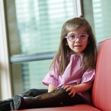 Girl with purple glasses with Neurological disorder sitting on couch.