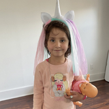 Young girl Afgahni refugee with unicorn headband and baby doll