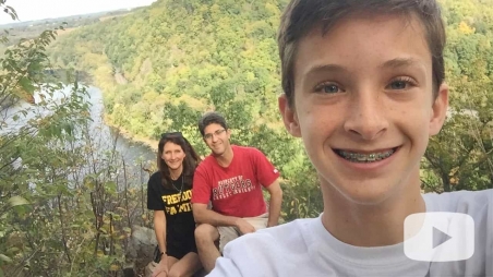 Connor selfie with parents and wooded valley behind him