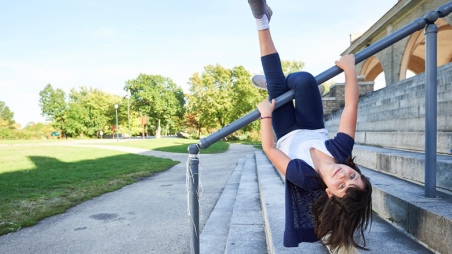Young girl hanging upside down on railing