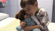 boy holding stuffed animal on hospital bed
